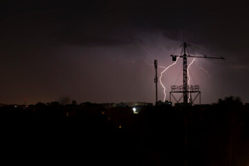 Thunder and storm in the city. Lightning strikes the tower crane