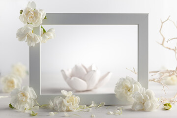 Still life with white flowers and frame on light backdrop. Creative concept for celebration of mother day, birthday, wedding or Valentines day
