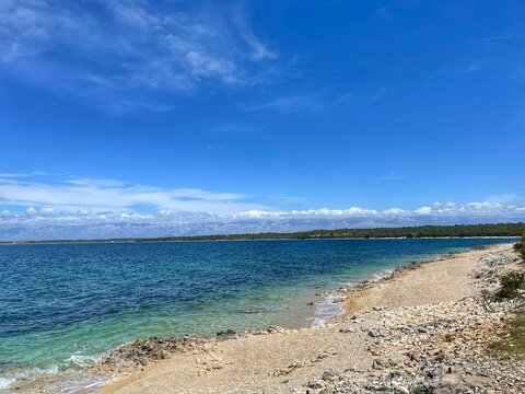 PETRČANE, CROATIA - June 2021. - Beautiful beach with rocks and pebbles in Petrčane near Zadar, Dalmatia on the Adriatic coast. Clean blue sea and sky