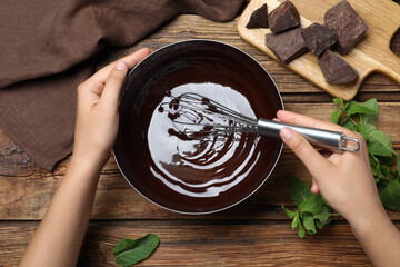 Woman making delicious chocolate cream at wooden table, top view