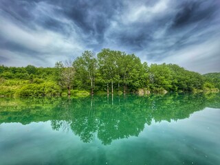 KOSINJ, CROATIA, June 2021 - Beautiful Lika river riverscape. Reflection in water and dramatic sky.
