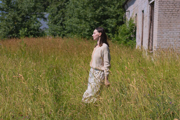 young woman in tall dry grass in a field in the midst of summer heat