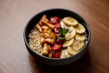 Vegetarian breakfast in a cafe: oatmeal with honey, caramelized bananas and apples, very beautiful appetizing shot