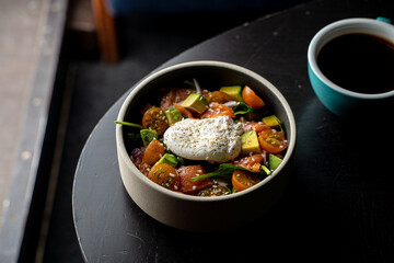 Gourmet salmon salad with a poached egg on a black round table in a restaurant