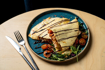 Mexican quesadilla with grilled chicken breast and mixed salad on a light wooden table, appetizing photo