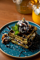 Close up of gourmet brussels waffles with vanilla ice cream and blueberry sauce