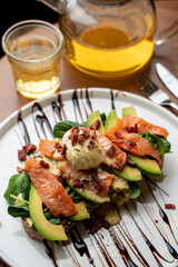 Summer healthy lunch in a cafe: salmon, avocado and spinach sandwich with a poached egg on top