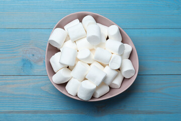 Delicious puffy marshmallows on light blue wooden table, top view