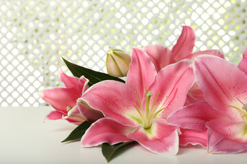 Beautiful pink lily flowers on white table, closeup