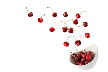 Fresh  ripe cherry berries falling into bowl isolated on white background.