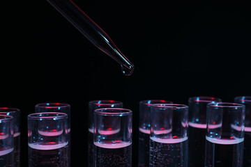 Dripping reagent into test tube on black background, closeup. Laboratory analysis