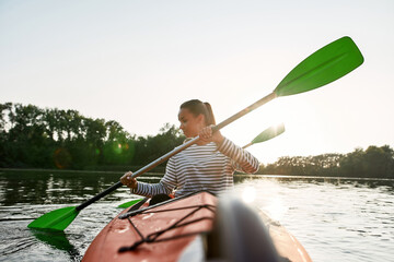 Active young woman enjoying kayaking with her boyfriend in a lake on a summer day