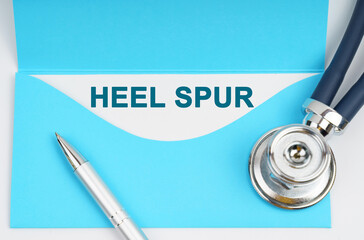 There is a stethoscope on the table, an envelope with paper on which it is written - Heel Spur