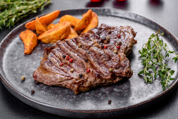 Delicious juicy fresh beef steak with spices and herbs on a dark concrete background