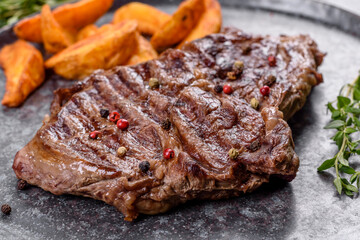 Delicious juicy fresh beef steak with spices and herbs on a dark concrete background