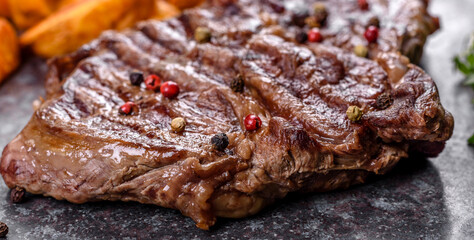 Delicious juicy fresh beef steak with spices and herbs on a dark concrete background