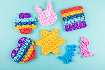 Set of popular colorful fidget toys pop it on blue background. New sensory anti-stress toys for children and adult. Trendy push bubble toys. Flat lay. - obrazy, fototapety, plakaty