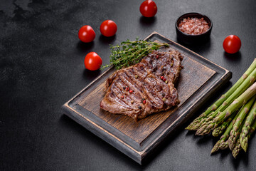 Delicious juicy fresh beef steak with spices and herbs on a dark concrete background