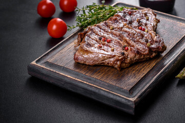 Delicious juicy fresh beef steak with spices and herbs on a dark concrete background