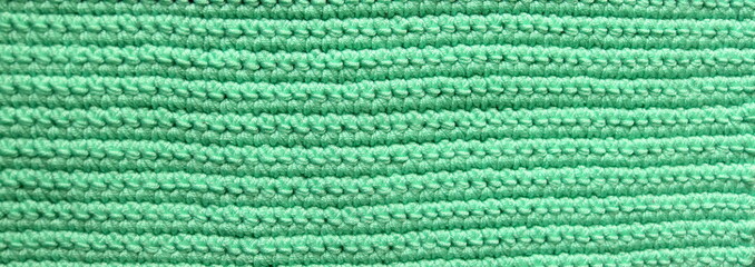 Knitted background, knitted wallpaper, knitted fabric, ricotted texture. Soft material. Handmade carpet closeup photo. Cozy background. Knitted details. 