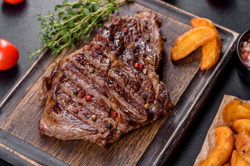 Delicious juicy fresh beef steak with spices and herbs on a dark concrete background