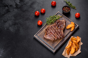 Delicious juicy fresh beef steak with spices and herbs on a dark concrete background