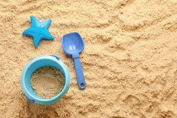 Flat lay of beach toy kit on sand, space for text. Outdoor play