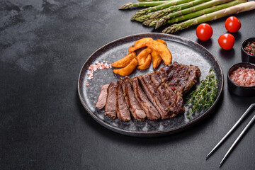 Delicious juicy fresh beef steak with spices and herbs on a dark concrete background