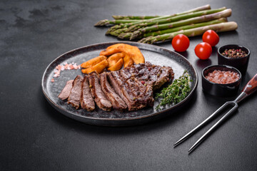 Delicious juicy fresh beef steak with spices and herbs on a dark concrete background