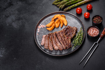 Delicious juicy fresh beef steak with spices and herbs on a dark concrete background