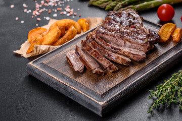 Delicious juicy fresh beef steak with spices and herbs on a dark concrete background