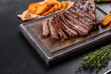 Delicious juicy fresh beef steak with spices and herbs on a dark concrete background