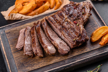 Delicious juicy fresh beef steak with spices and herbs on a dark concrete background