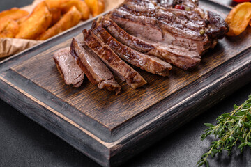 Delicious juicy fresh beef steak with spices and herbs on a dark concrete background