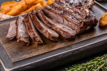 Delicious juicy fresh beef steak with spices and herbs on a dark concrete background
