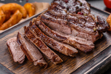 Delicious juicy fresh beef steak with spices and herbs on a dark concrete background