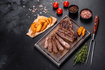 Delicious juicy fresh beef steak with spices and herbs on a dark concrete background