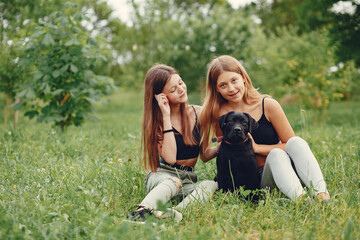 Two cute girls in a summer park with a dog