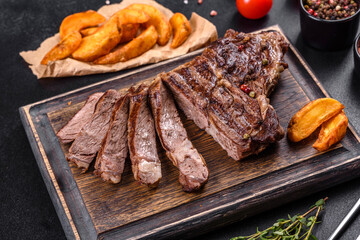 Delicious juicy fresh beef steak with spices and herbs on a dark concrete background
