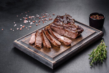 Delicious juicy fresh beef steak with spices and herbs on a dark concrete background