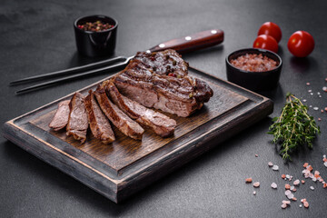 Delicious juicy fresh beef steak with spices and herbs on a dark concrete background