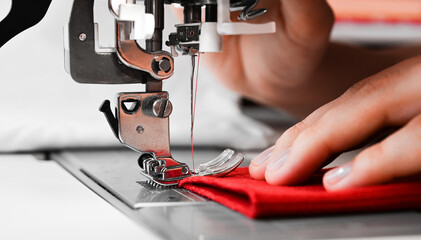 Woman's hands with red fabrics at sewing machine. Self made clothes concept.Hobby concept. Clothes repairing concept. - obrazy, fototapety, plakaty