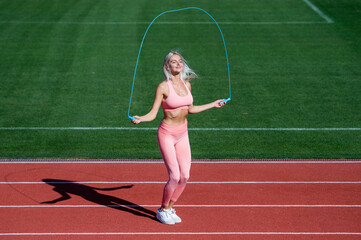 Fototapeta premium energetic woman jumping with rope. sporty girl in sportswear jump on skipping rope.