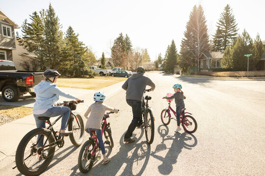 Rear view of family riding bicycles in suburban neighborhood