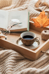Fototapeta na wymiar Coffee in bed, romantic morning. Open book and a cup of coffee on a wooden tray. Home cozy interior, lifestyle. Selective focus