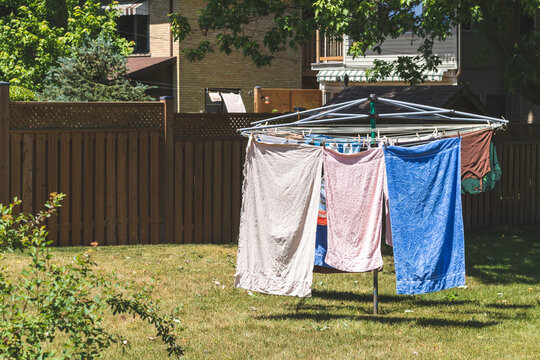 Metal outdoor clothes drying rack with towels and a shirt drying on it. On backyard lawn. Vintage filter. 