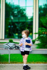 a little girl is standing near the school, with a diary in her hand, sad,in a bad mood