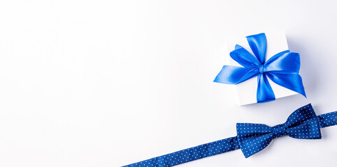 Gift dad. Blue bowtie or tie, white box with bow ribbon on light background. Happy loving family and Fathers Day concept.