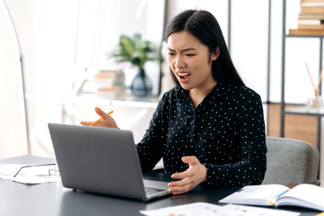 Unpleasant video conversation. Annoyed asian girl, ceo, office worker, irritated talking with...