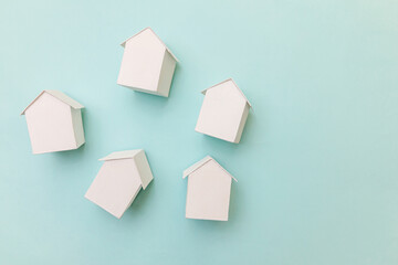 Simply flat lay design with miniature white toy model houses isolated on pastel blue background. Mortgage property insurance dream home concept. Flat lay top view copy space.
